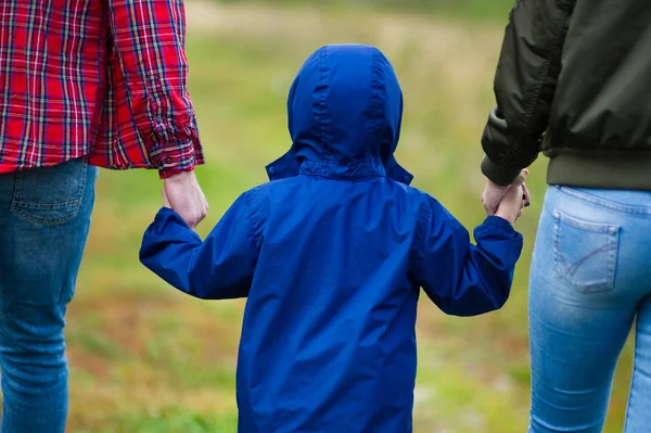 Föräldrarna håller barnet i händerna, bakifrån. — Stockfoto