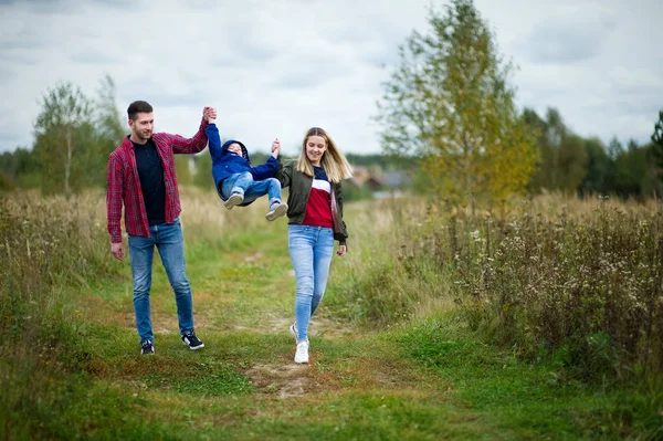 Eltern in Freizeitkleidung gehen mit kleinem Sohn auf Landstraße — Stockfoto