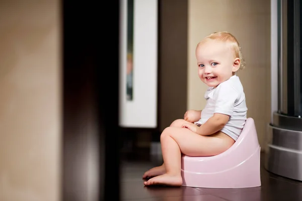 Kleines Mädchen sitzt auf einem Topf im Badezimmer und lächelt — Stockfoto