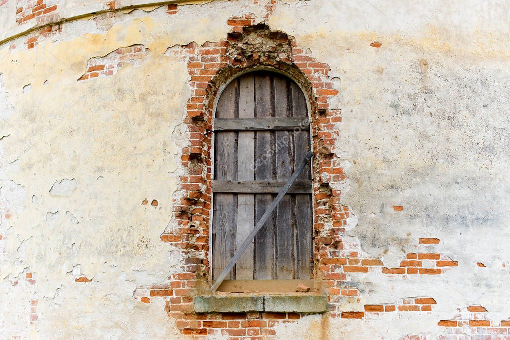 window of an old abandoned church boarded up with wooden boards