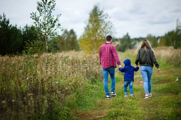 Föräldrar går med sin lille son längs en landsväg, bakifrån — Stockfoto