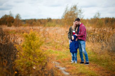 Genç bir aile - anne, baba ve küçük oğlu sonbahar öğleden sonra bir ülke yolda duruyor.