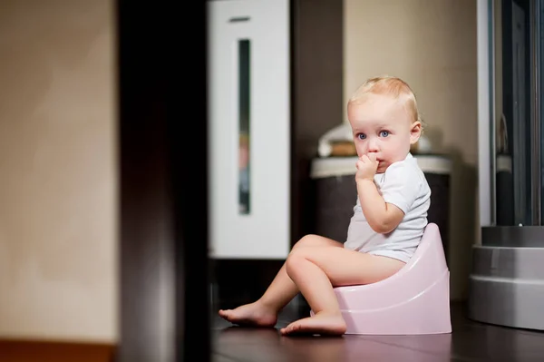Kleines Mädchen sitzt auf einem Topf im Badezimmer und sieht überrascht aus — Stockfoto