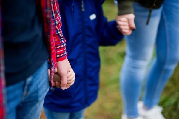 Kind in blauer Jacke hält Eltern an den Händen. Nahaufnahme von Händen, die sich berühren — Stockfoto