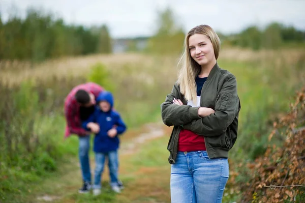 Ung kvinna ler, och i bakgrunden hennes pojkvän leker med liten unge — Stockfoto