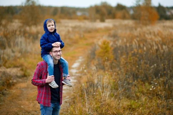 Sonen sitter på sin fars axlar. Vandra i byn — Stockfoto