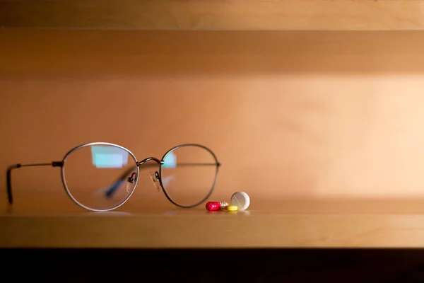 Gafas y pastillas se encuentra en un estante, espacio para copiar — Foto de Stock