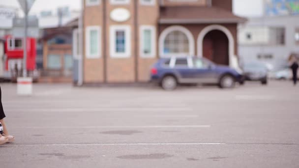 子供の車にコートを着た若い女性が駐車場に乗る フレームに出入りすると 背景がぼやける — ストック動画