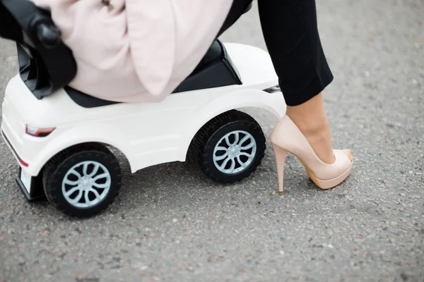 Kaldırımda duran bir bebek araba üzerinde oturan bir kadının bacaklarının yakın çekim — Stok fotoğraf