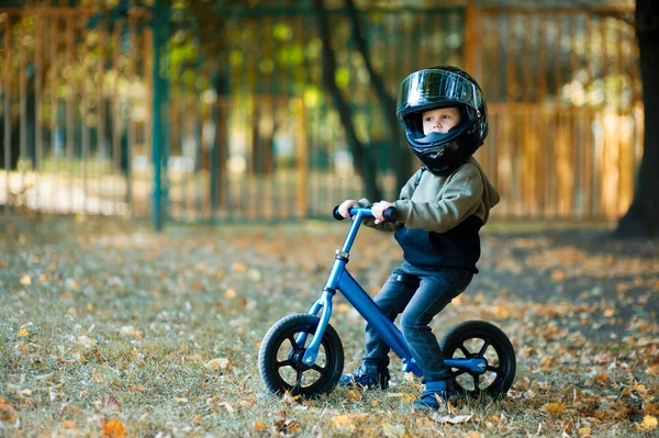 Der Junge auf dem Roller ist zu sehr durch einen großen Motorradhelm geschützt — Stockfoto