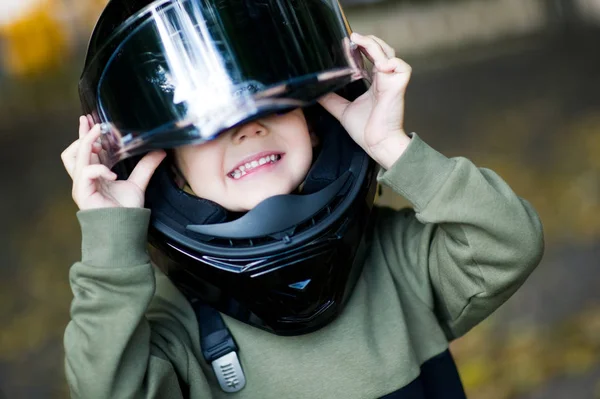 Il ragazzo affogato in un casco da moto di grandi dimensioni, che non è affatto della sua taglia — Foto Stock