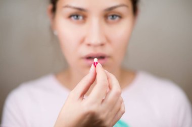 Renk hapı ve ilaç almak üzere olan uykulu görünümlü bir kadın.