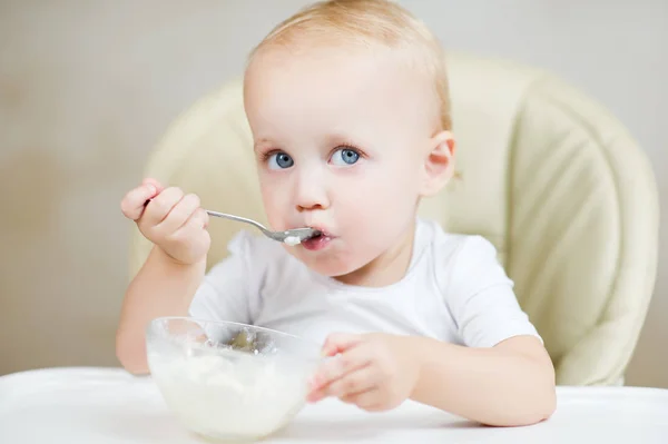 Niña mira a la cámara, sosteniendo una cuchara y a punto de comer gachas —  Fotos de Stock