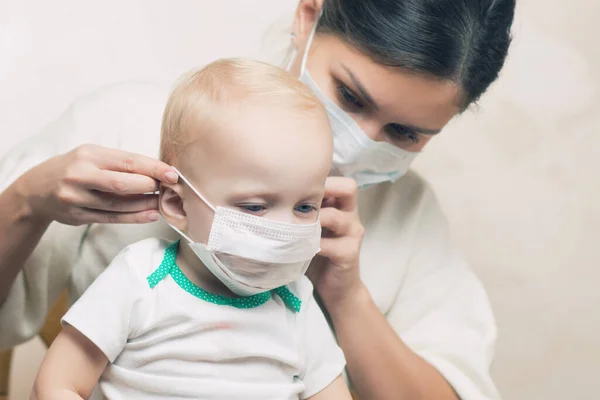 Anne küçük kızına tıbbi maske takıyor. — Stok fotoğraf