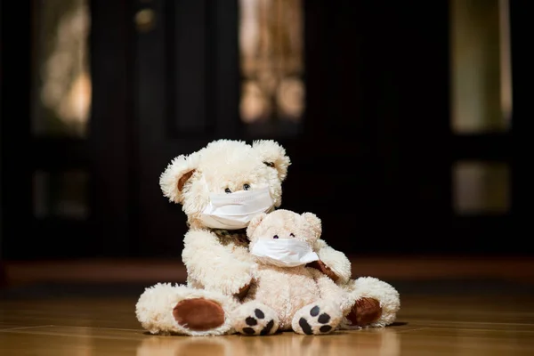 Two teddy bears in medical masks are sitting near the door — Stock Photo, Image