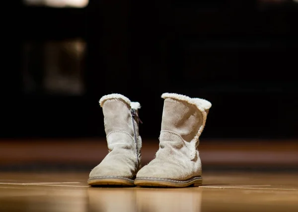 Children 's boots stand lonely near the front door of the house, close up — стоковое фото