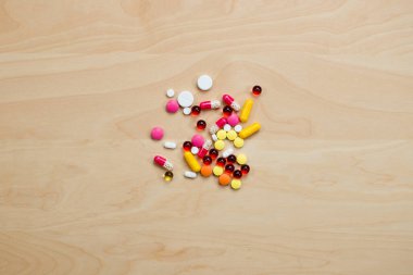 Bir avuç renkli hap açık tahta bir masada yatıyor.