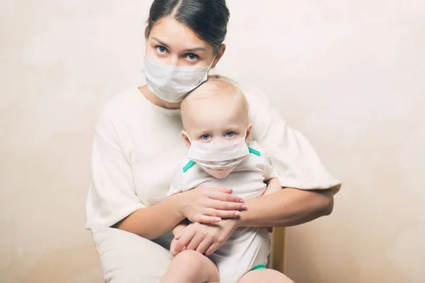 Mère étreint sa petite fille, les deux masques médicaux regardent tristement — Photo