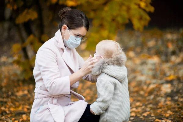 Tıbbi maskeli bir anne, tıbbi maskeyi küçük kızına göre ayarlıyor. — Stok fotoğraf