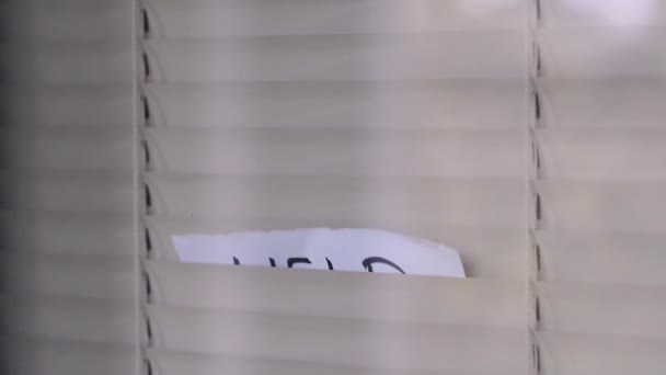男人透过百叶窗发出呼救信号 呼救信号写在一张纸上 百叶窗上出现了一张写有 字样的纸 — 图库视频影像