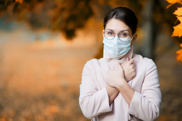 Une fille portant un masque médical et des lunettes ferme son col de manteau plus étroitement pendant la maladie et le froid. Espace de copie — Photo