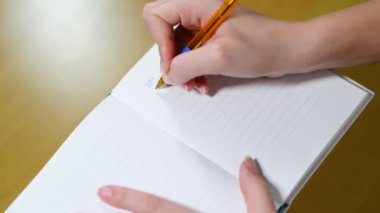 Kadın hesaplamaları deftere numaralar yazarak ve özetleyerek yapıyor.