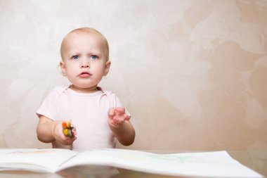 Çok üzgün bir çocuk elinde kalem ve boya kalemi tutuyor.