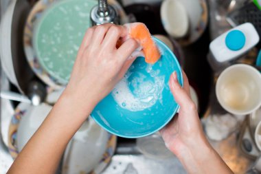 Kız lavaboda bulaşıkları yıkıyor.