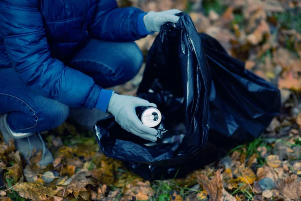 Chica pone una lata de cerveza arrugada en una bolsa de basura, limpiar el bosque — Foto de Stock