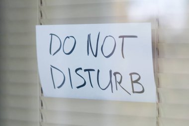 Rahatsız edilmeme isteği perdeler tarafından kapatılmış bir pencerede görülür