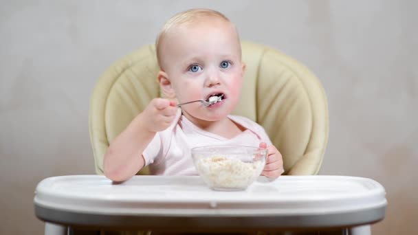 Niña Ineptamente Come Gachas Con Una Cuchara Una Silla Alimentación — Vídeo de stock