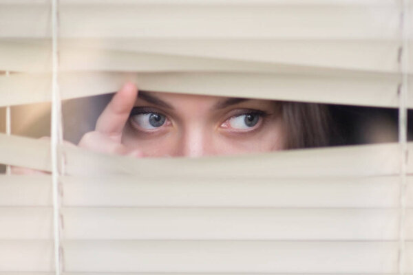girl peeps out through the blinds