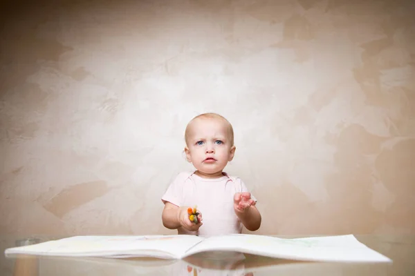 Ένα μικρό κορίτσι στέκεται πάνω από ένα μπλοκ ζωγραφικής, κρατά μολύβια και μαρκαδόρους και φαίνεται πολύ αυστηρά μπροστά της. — Φωτογραφία Αρχείου