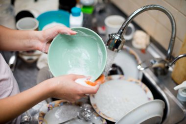 Eldivensiz bir kız kirli bir tabak yıkar.