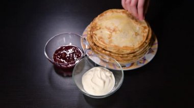 Kız ince bir krep çevirir ve onu ekşi kremaya batırır.