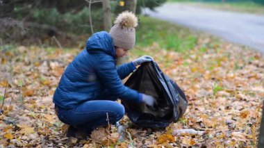 Kadın ormanın bölgesini temizliyor, torba içinde çöp topluyor.