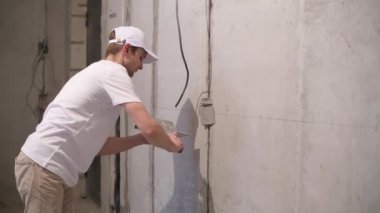 Bir işçi, duvarında bir kablo olan beton havan topu ile bir kanalı kapatır. Dairedeki işi bitiriyorum.