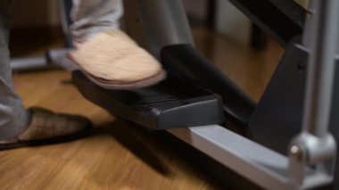Terlikli bir kız spor makinesine biner ve tembel bir antrenmana başlar, bacaklarını kapatır.