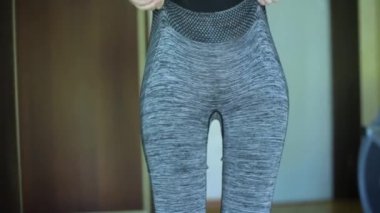 Bir kızın arka görünüşü üzerine spor tozluklarını giyer ve evde spor antrenmanlarına hazırlanır. Kapatın, evde yüz bakımı ve spor yok.