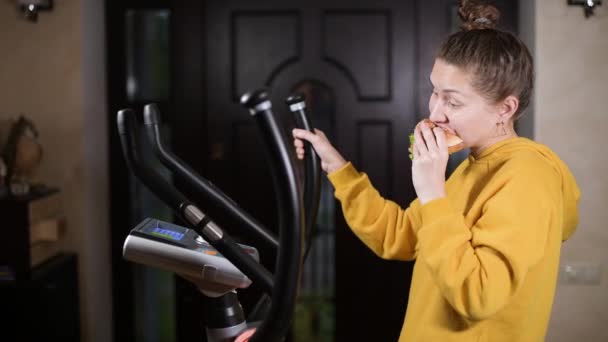 Evde Bir Elipsoidin Üzerinde Egzersiz Yapıp Hamburger Yemek Yaramaz Egzersizler — Stok video