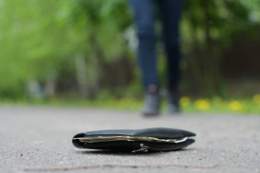 Adam, parktaki asfalt yolda duran cüzdana gidiyor. Kayıp bir cüzdan bulunması