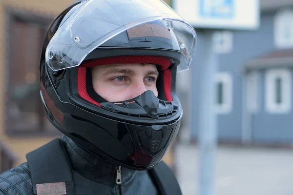 Side view of a biker in a helmet with an open visor. Biker looks straight