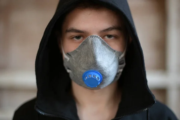 作業用のマスクを着た10代の若者がカメラを直接見て放棄された部屋にいる — ストック写真