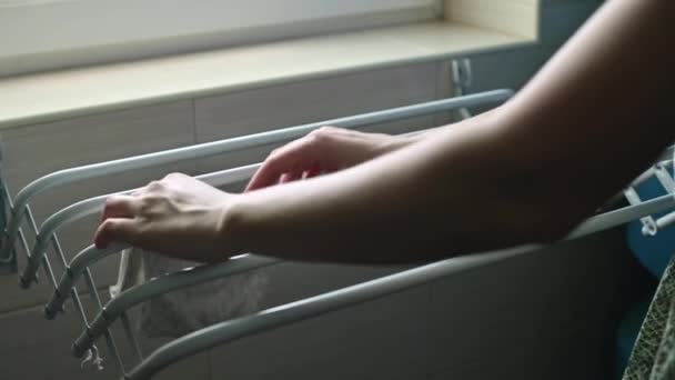 Μια γυναίκα κρεμάει πλυμένα μωρουδιακά ρούχα στο στεγνωτήριο. Moms καθημερινή ρουτίνα — Αρχείο Βίντεο