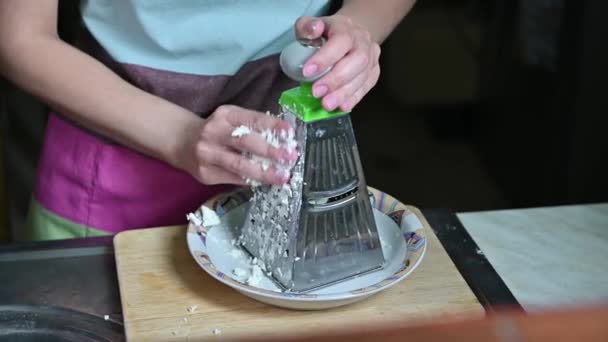 Žena masíruje měkký sýr na struhadle při přípravě večeře doma — Stock video