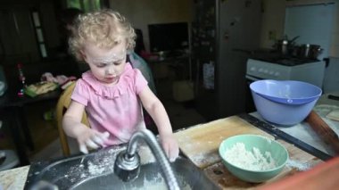 Annem yemek yapmakla meşgulken küçük bir kız mutfakta kabadayılık yapıyor.