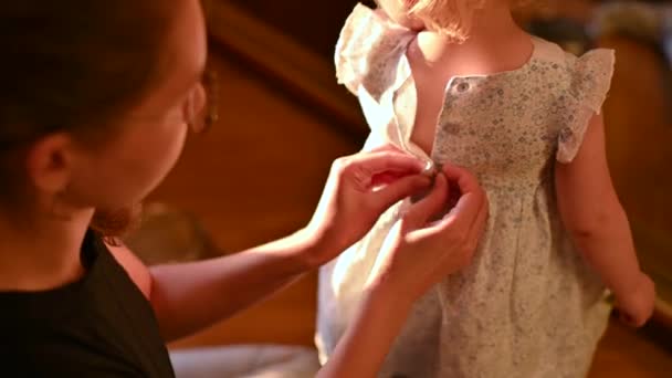엄마는 어린 딸의 드레스의 단추를 조심스럽게 누른다 — 비디오