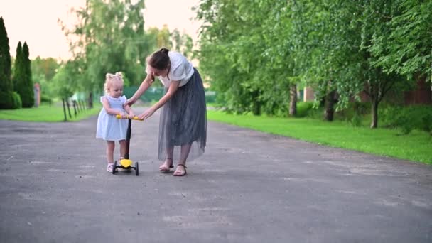Dziewczyna odjeżdża z matką na skuterze podczas letniego spaceru — Wideo stockowe