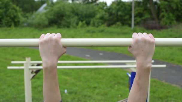 Adolescente appende fuori sulla barra orizzontale e tenta senza successo di tirarsi su — Video Stock