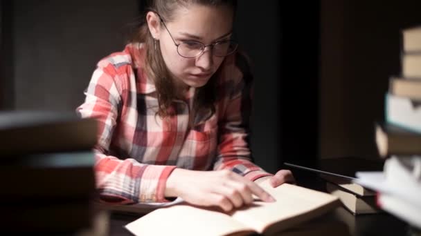 Ragazza cerca informazioni nel libro, ma non lo trova, quindi prende tablet — Video Stock